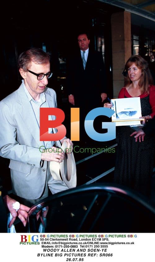 Woody Allen enters car in pale suit and panama hat