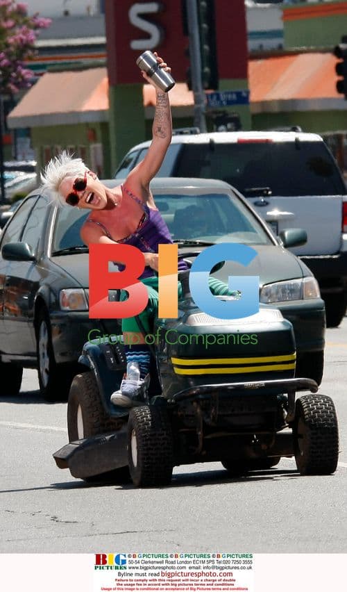 Pink drives lawn mower on Sunset