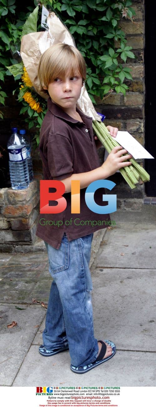 Young visitor presents flowers at Amy Winehouse home