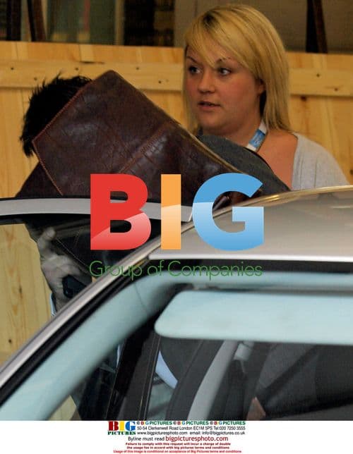 Lee McQueen shields face from press