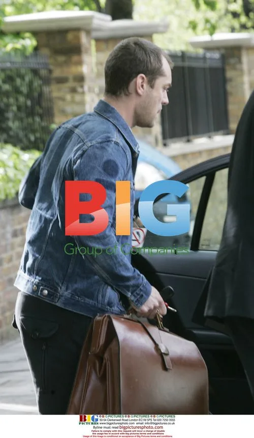 Jude Law waits for lift with luggage in London