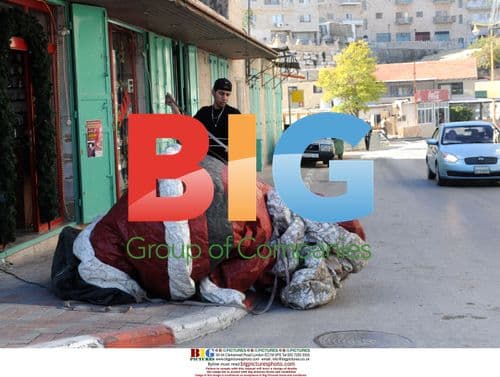 Palestinian prepares to lift Santa in Bethlehem